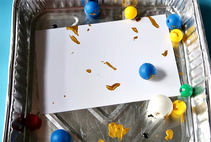 Marbles move ink dropped in from Delicata inkers across white cardstock in a disposable tray.