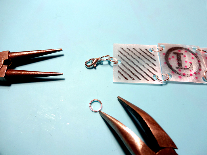 Jewelers pliers are used to attache jump rings and clasp to a handmade bracelet made from Imagine's Vertigo sheets stamped with StazOn ink by Kyriakos Pachadiroglou.