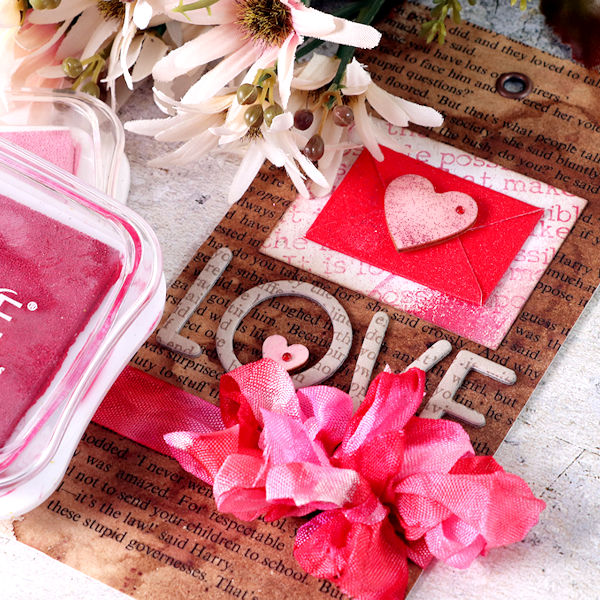 Today, I am sharing a quick Valentine's day tag, showing you how to color old book paper, create a fun brayered background with Memento Luxe ink pads and multicolored ribbon.